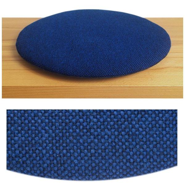 Das foto zeigt eine runde sitzauflage der firma discus. Das sitzkissen verjüngt sich zum rand hin und bildet eine schattenfuge aus. Die farbe der sitzauflage ist blau-schwarz meliert.