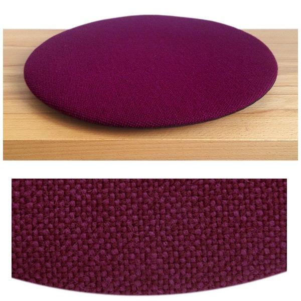 Das foto zeigt eine runde sitzauflage der firma discus. Das sitzkissen verjüngt sich zum rand hin und bildet eine schattenfuge aus. Die farbe der sitzauflage ist violett-bordaux meliert.