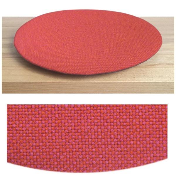 Das foto zeigt eine runde sitzauflage der firma discus. Das sitzkissen verjüngt sich zum rand hin und bildet eine schattenfuge aus. Die farbe der sitzauflage ist pink-orange meliert.