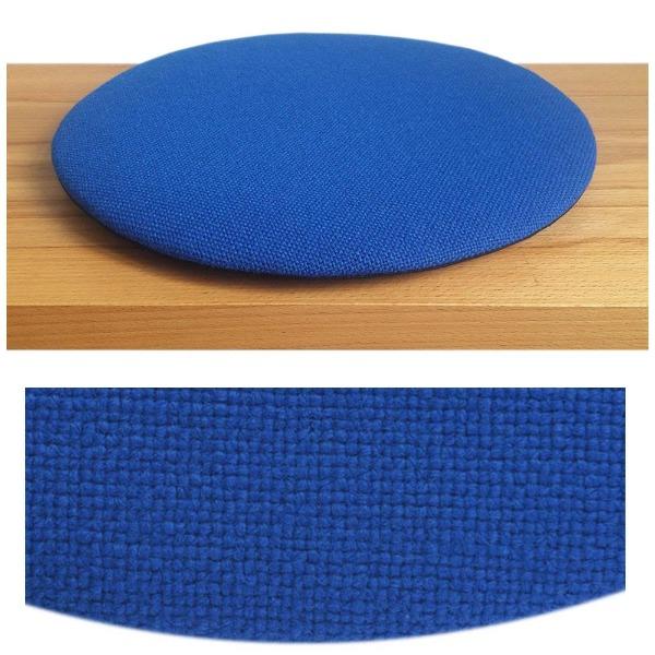 Das foto zeigt eine runde sitzauflage der firma discus. Das sitzkissen verjüngt sich zum rand hin und bildet eine schattenfuge aus. Die farbe der sitzauflage ist blau.